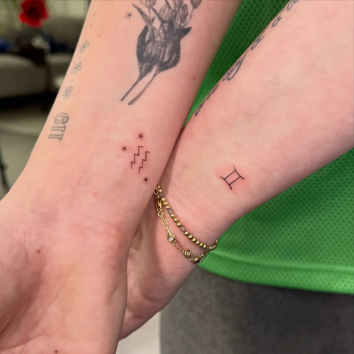 Two friends, zodiac signs on the wrists: Aquarius and Gemini, fine line tattoo