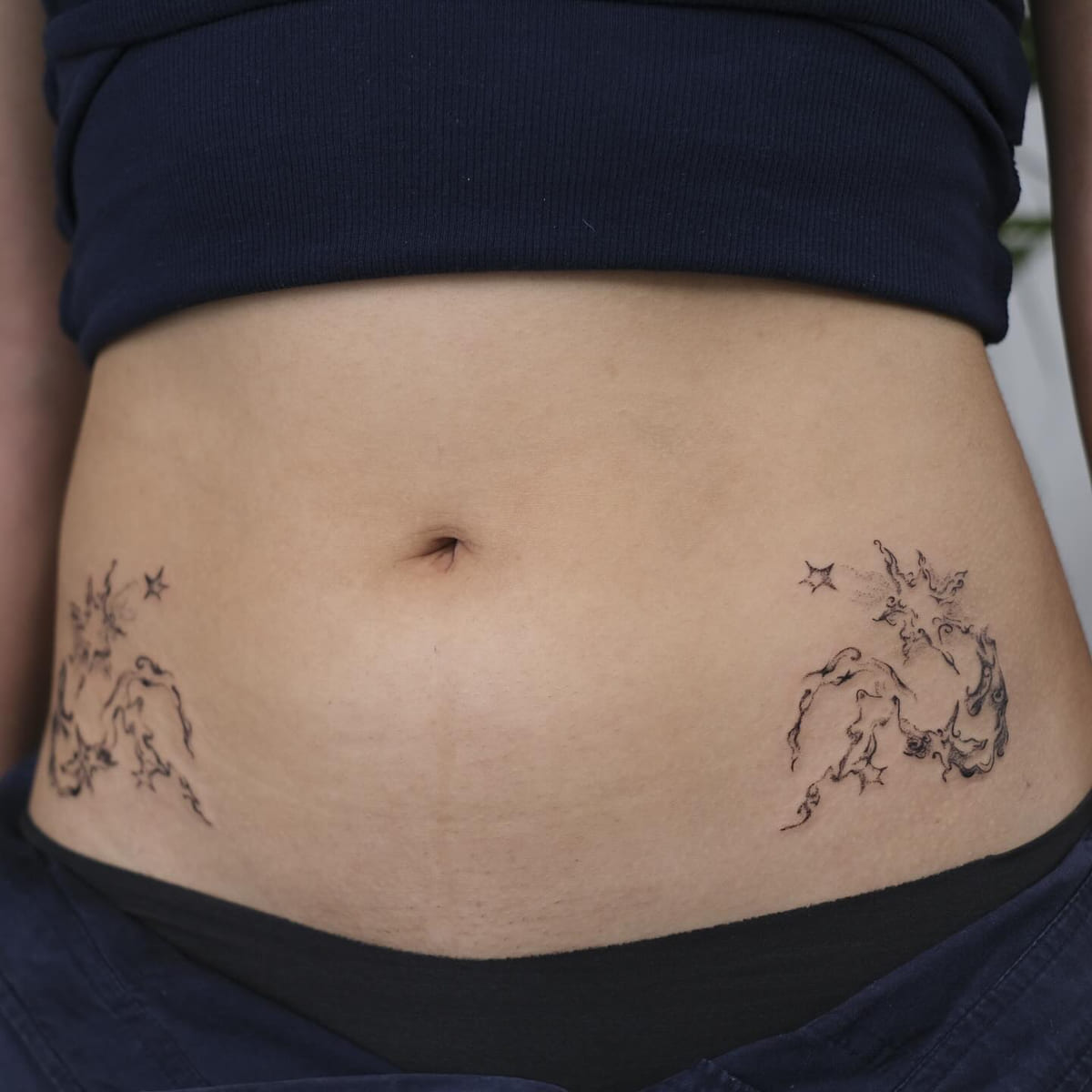 Pair of ornamental hip pieces with stars, mirrored, fine line tattoo