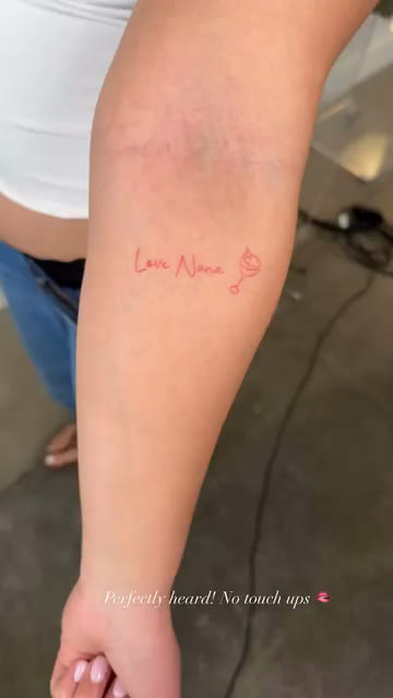 Red handwriting on an inner arm, healed fine line tattoo