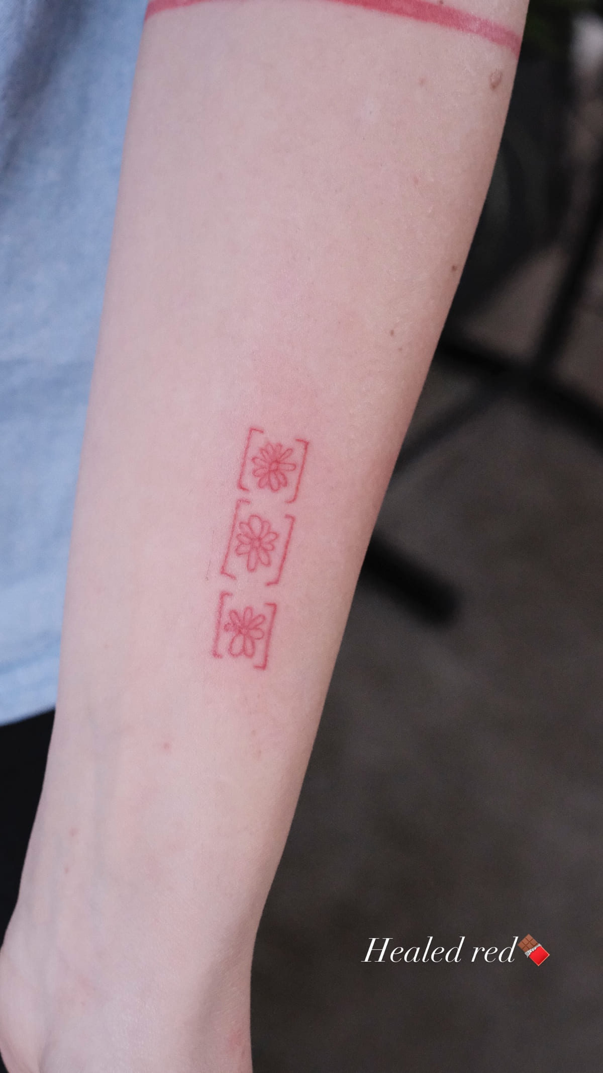 Three small red seal squares down a forearm, healed fine line tattoo, healed
