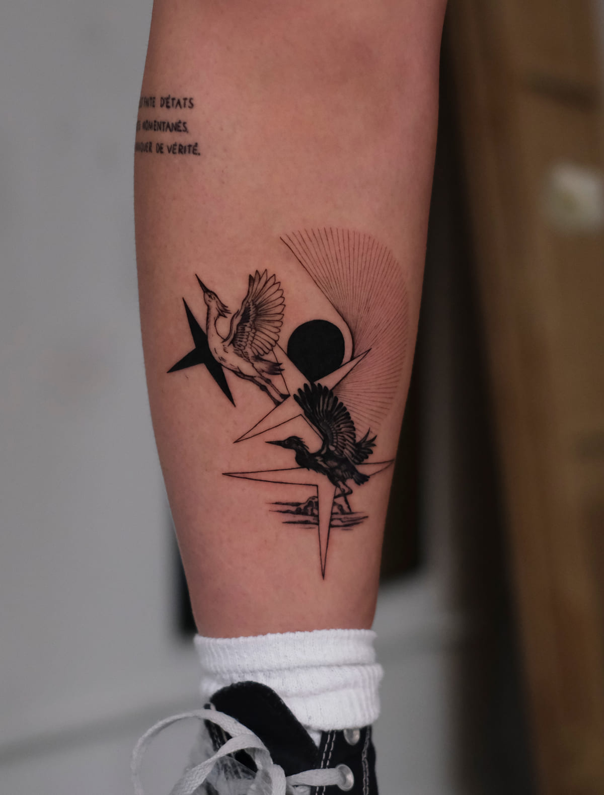 Graphic composition of cranes, solid shapes, a sun and fine fan lines, fine line tattoo