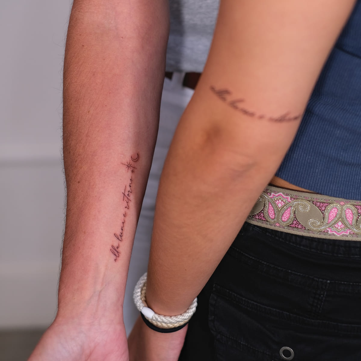 Two people with script lines along the forearm, fine line tattoo