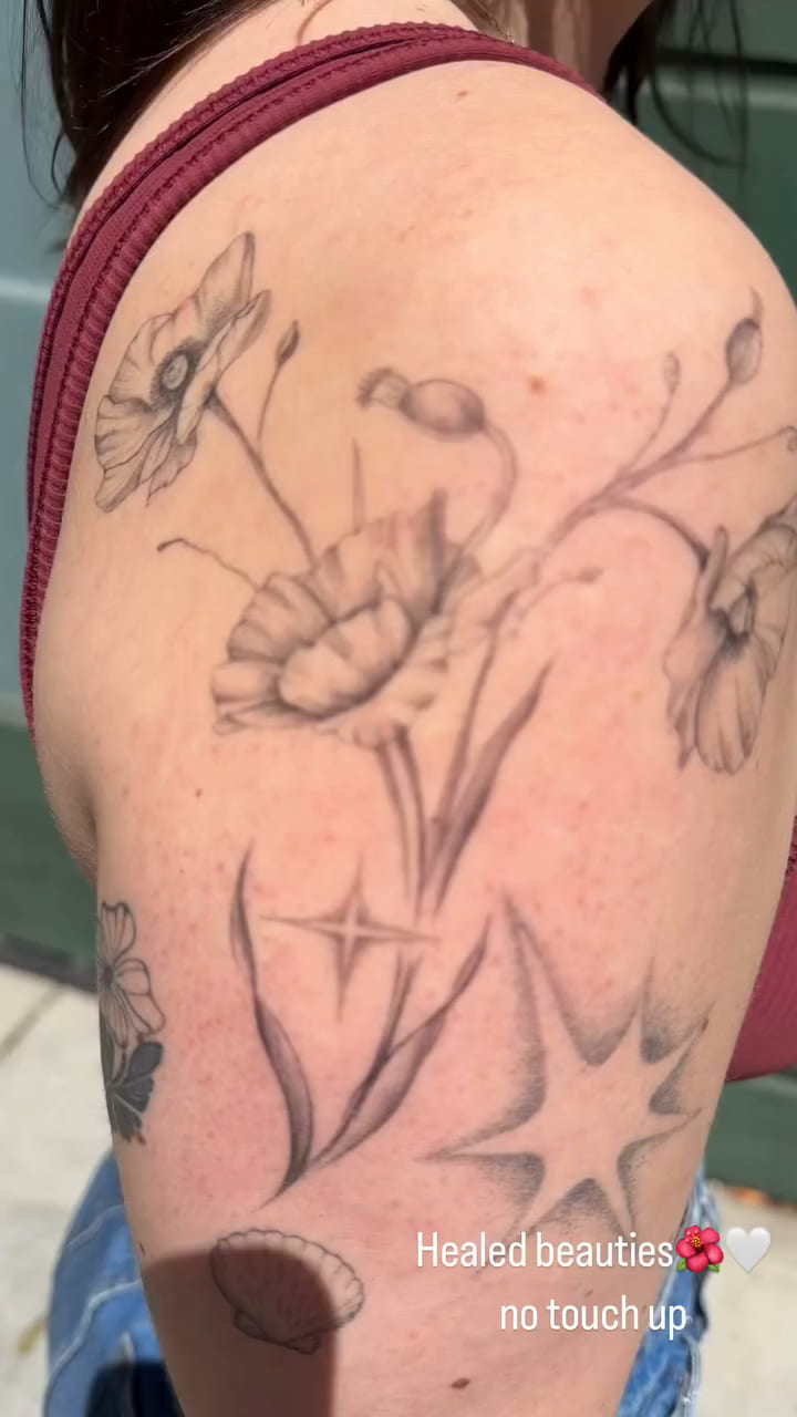 Poppies and sparkle stars across a shoulder, healed fine line tattoo