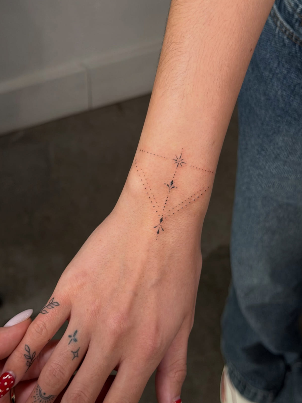 Dotwork ornament with small stars across wrist and hand, fine line tattoo