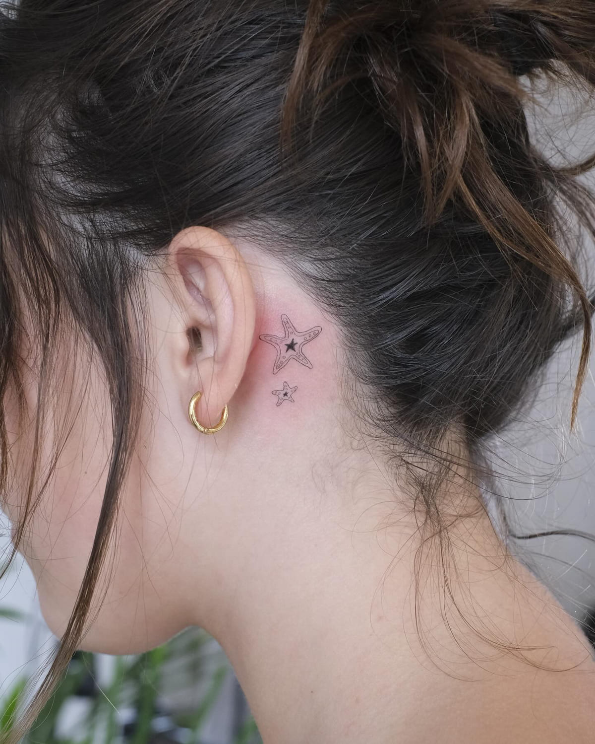 Two starfish behind the ear, fine line tattoo