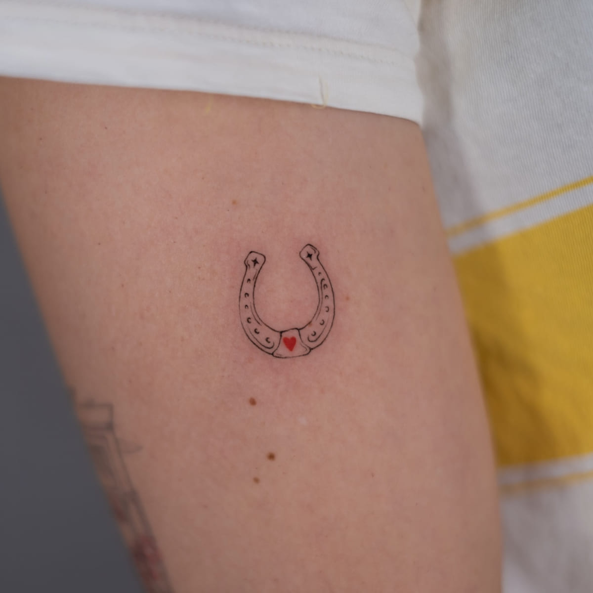 Horseshoe with a red heart, fine line tattoo