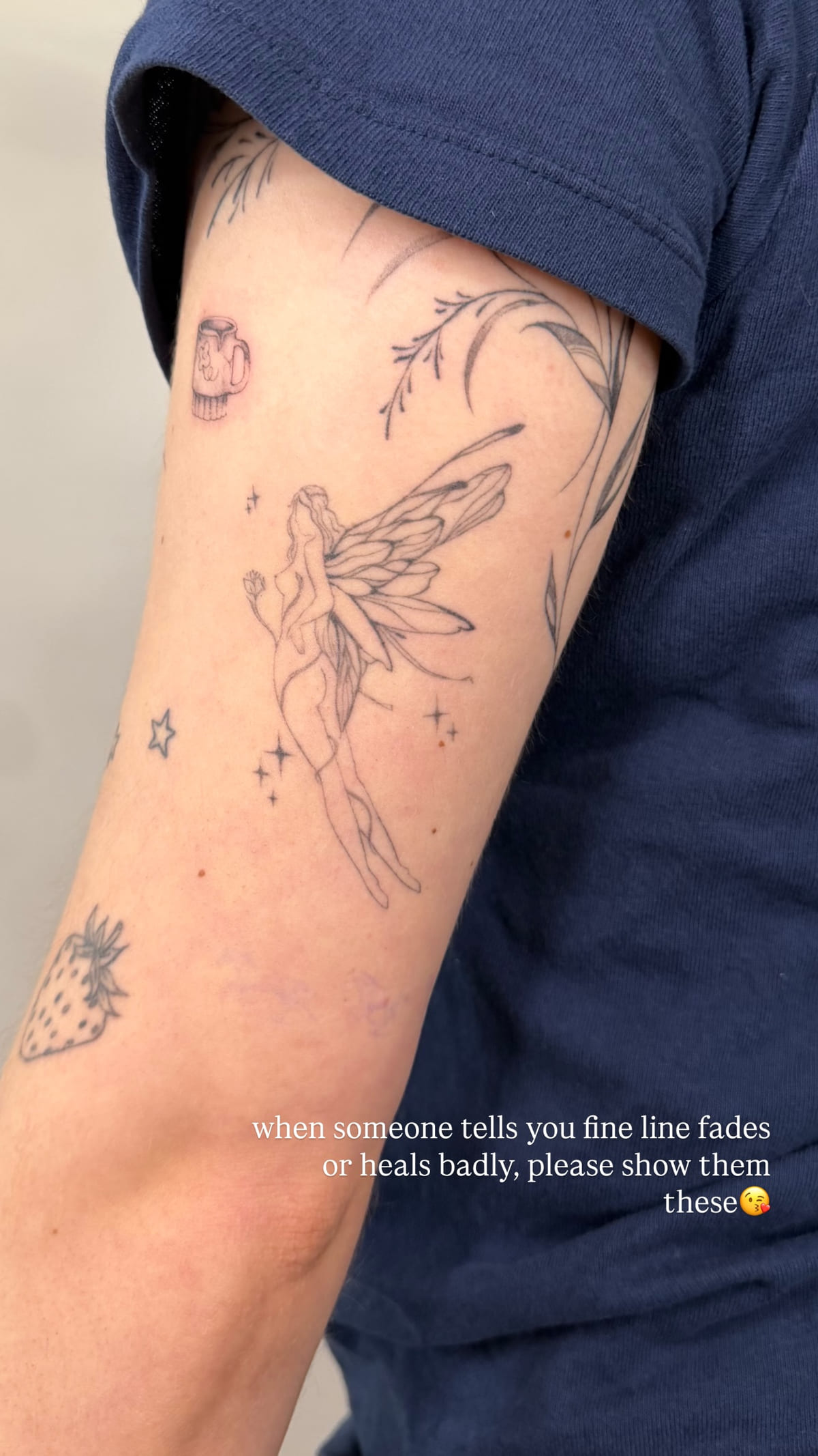 Fairy with tall wings on an upper arm, healed fine line tattoo