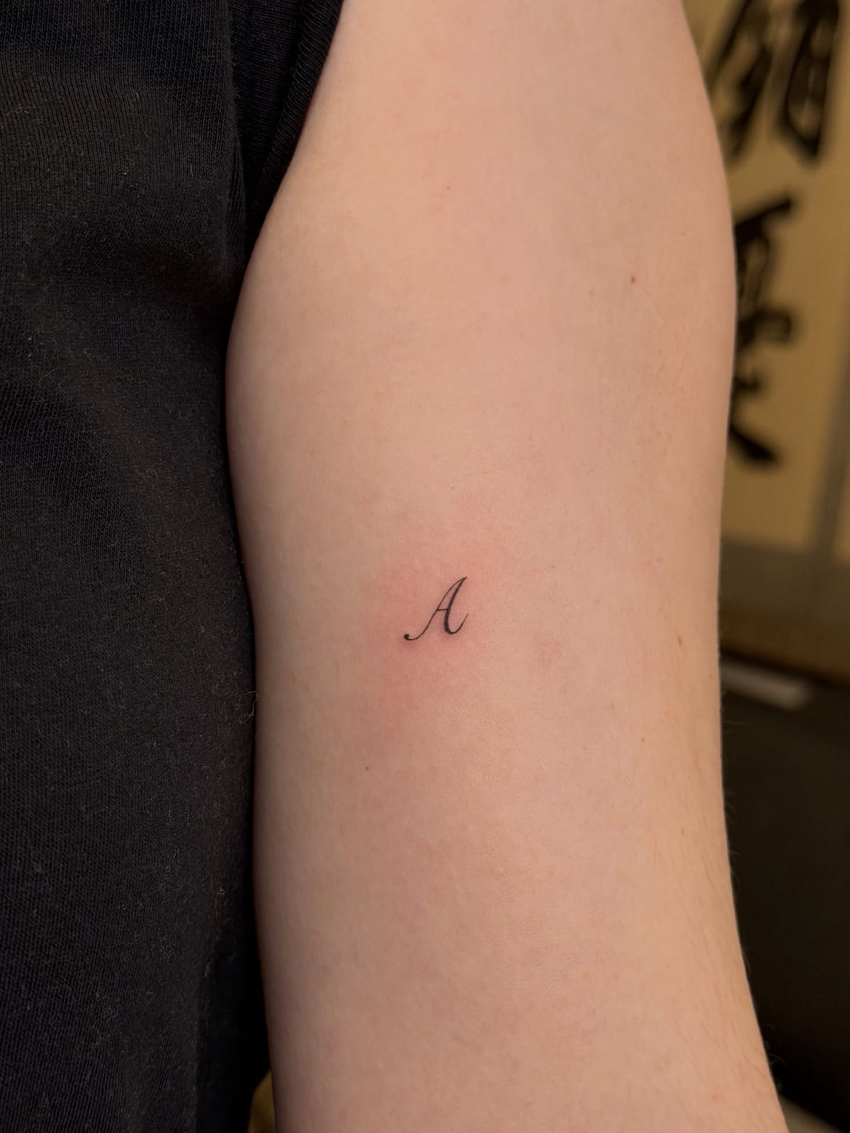 Tiny script initial A, fine line tattoo