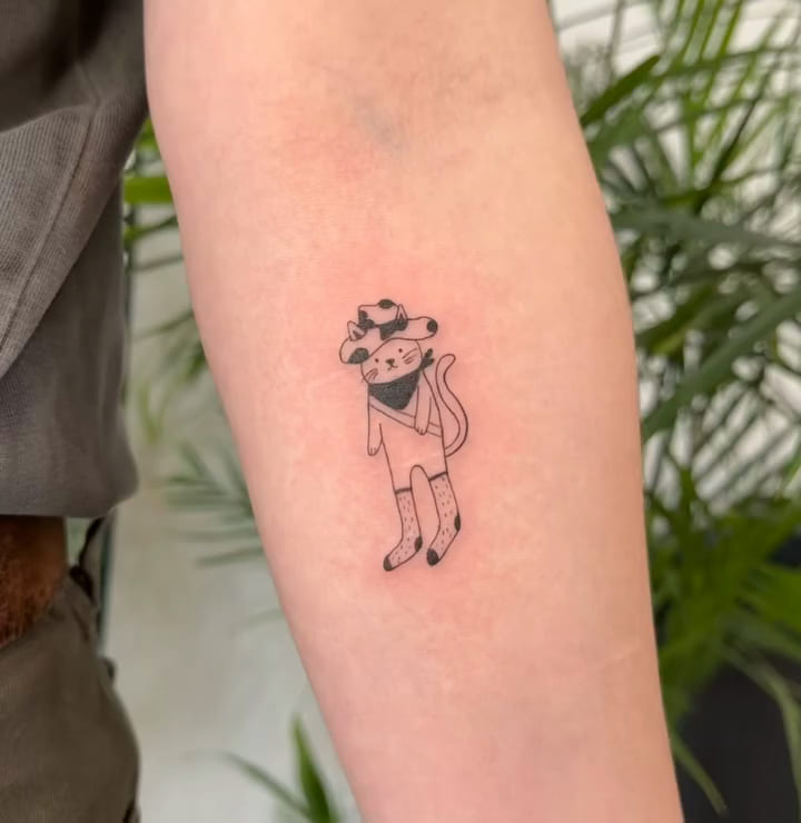 Cat in a cow print cowboy hat, bandana and socks, fine line tattoo