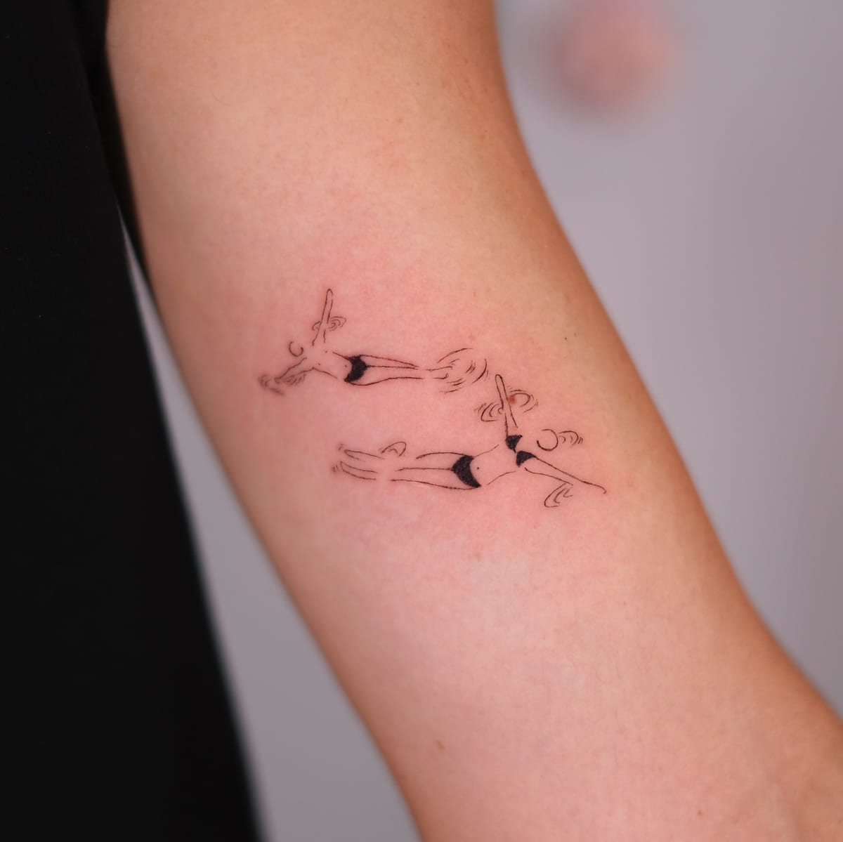 Matching swimmers on two people, fine line tattoo