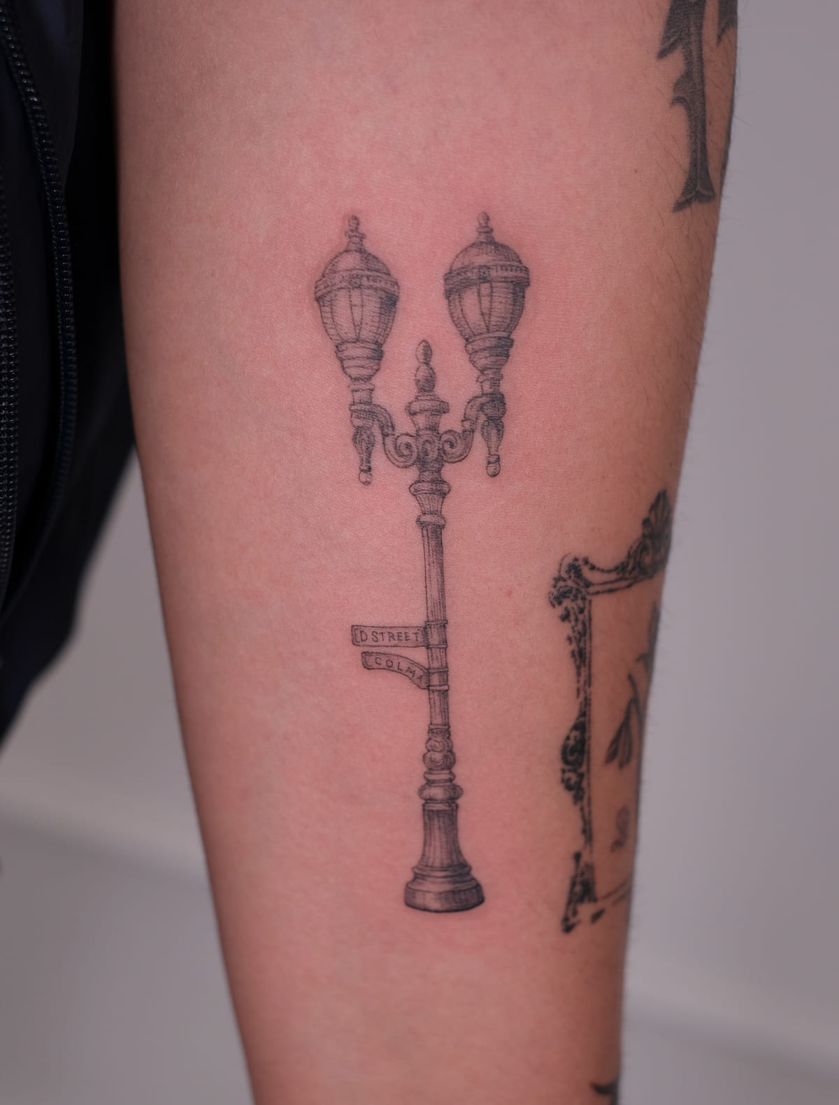 Double street lamp with street signs, fine line tattoo