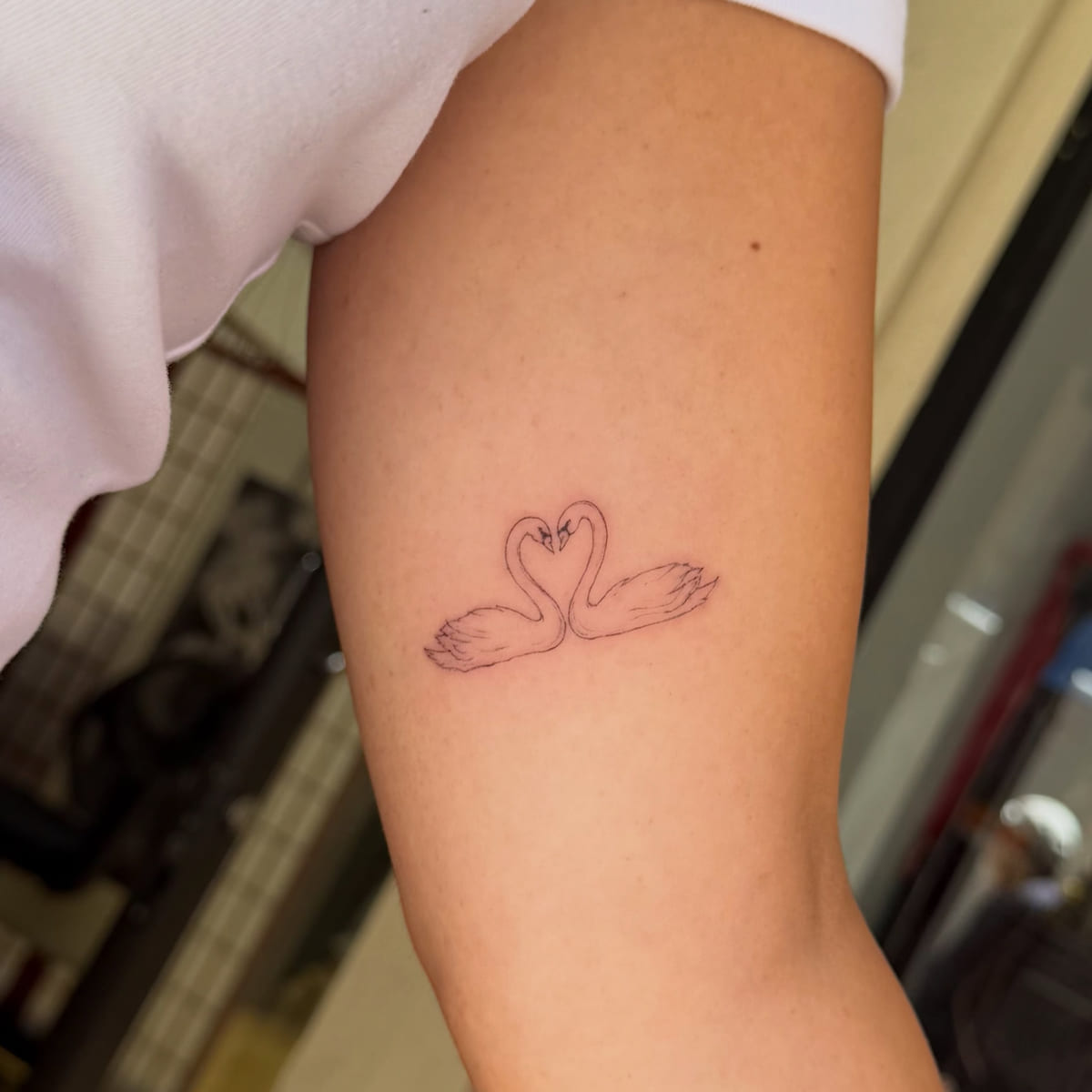 Two swans forming a heart, fine line tattoo