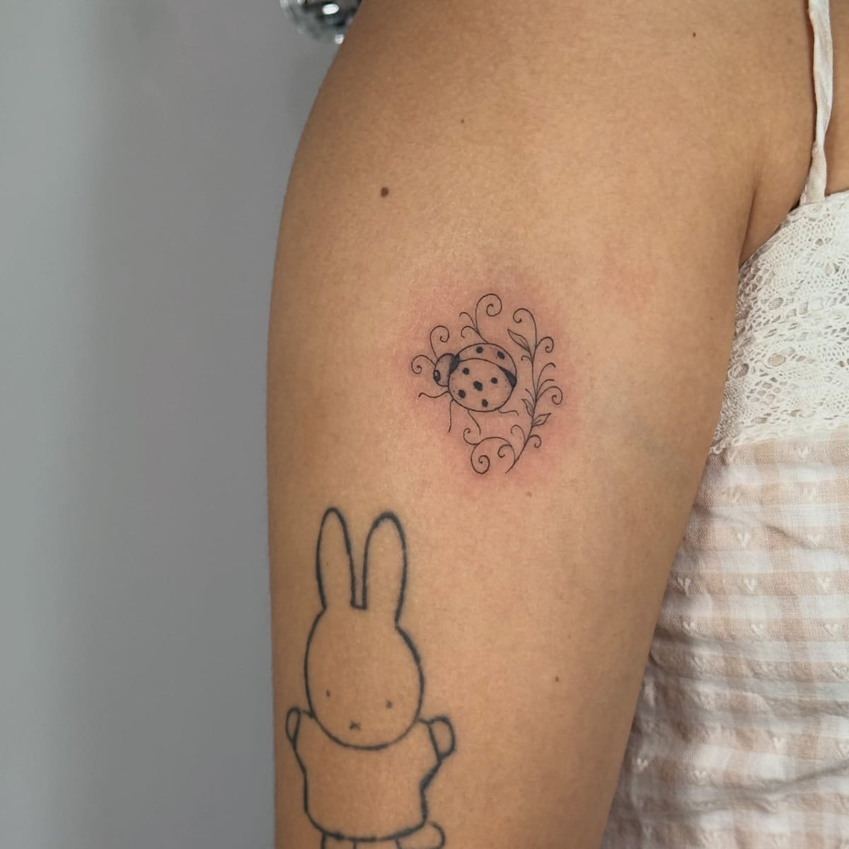 Ladybug among swirls, fine line tattoo