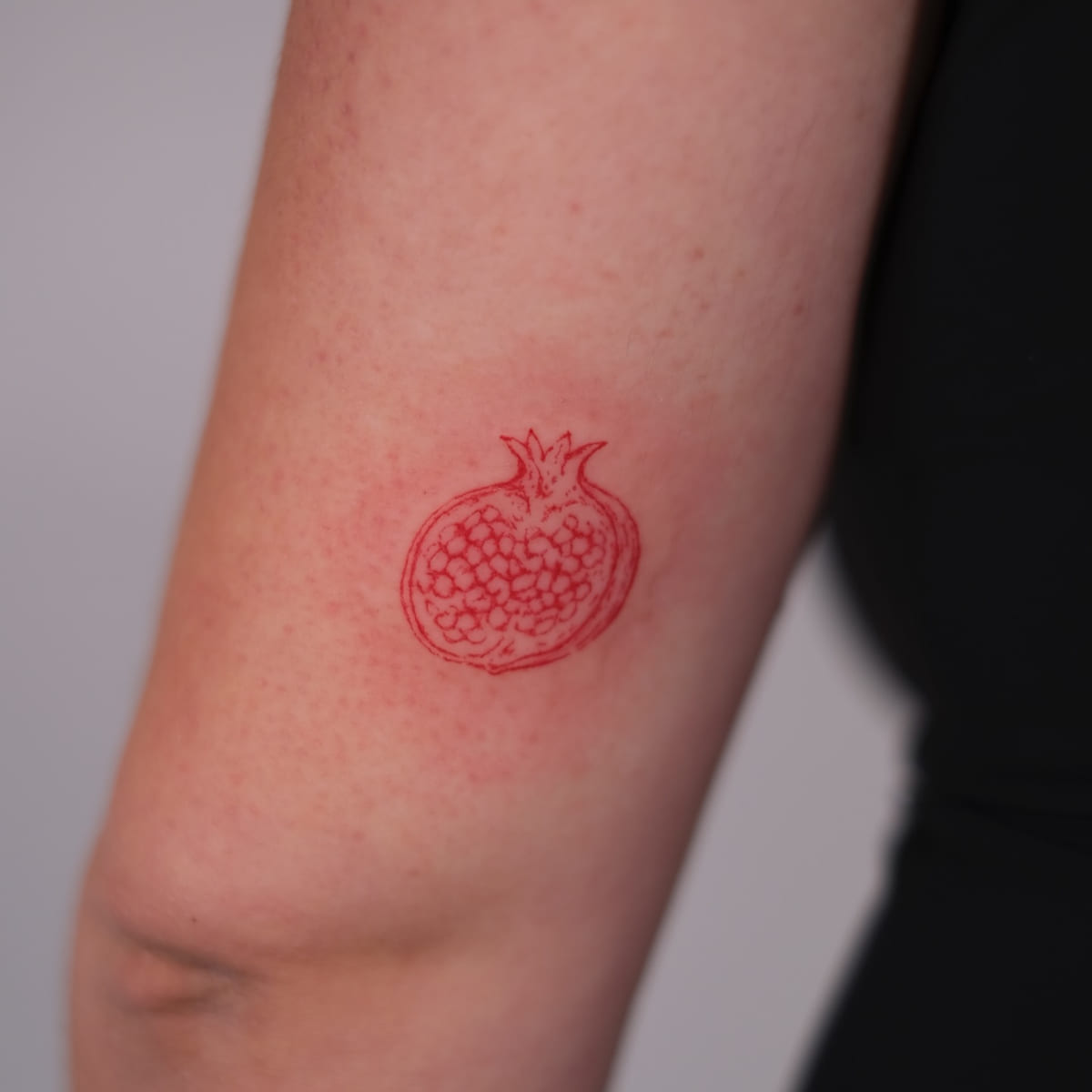 Pomegranate half in red, fine line tattoo