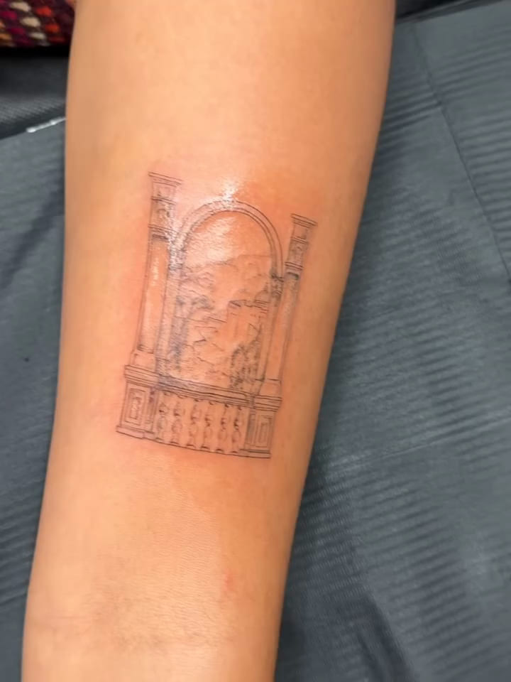Arched window with columns and balustrade framing a hillside town, fine line tattoo