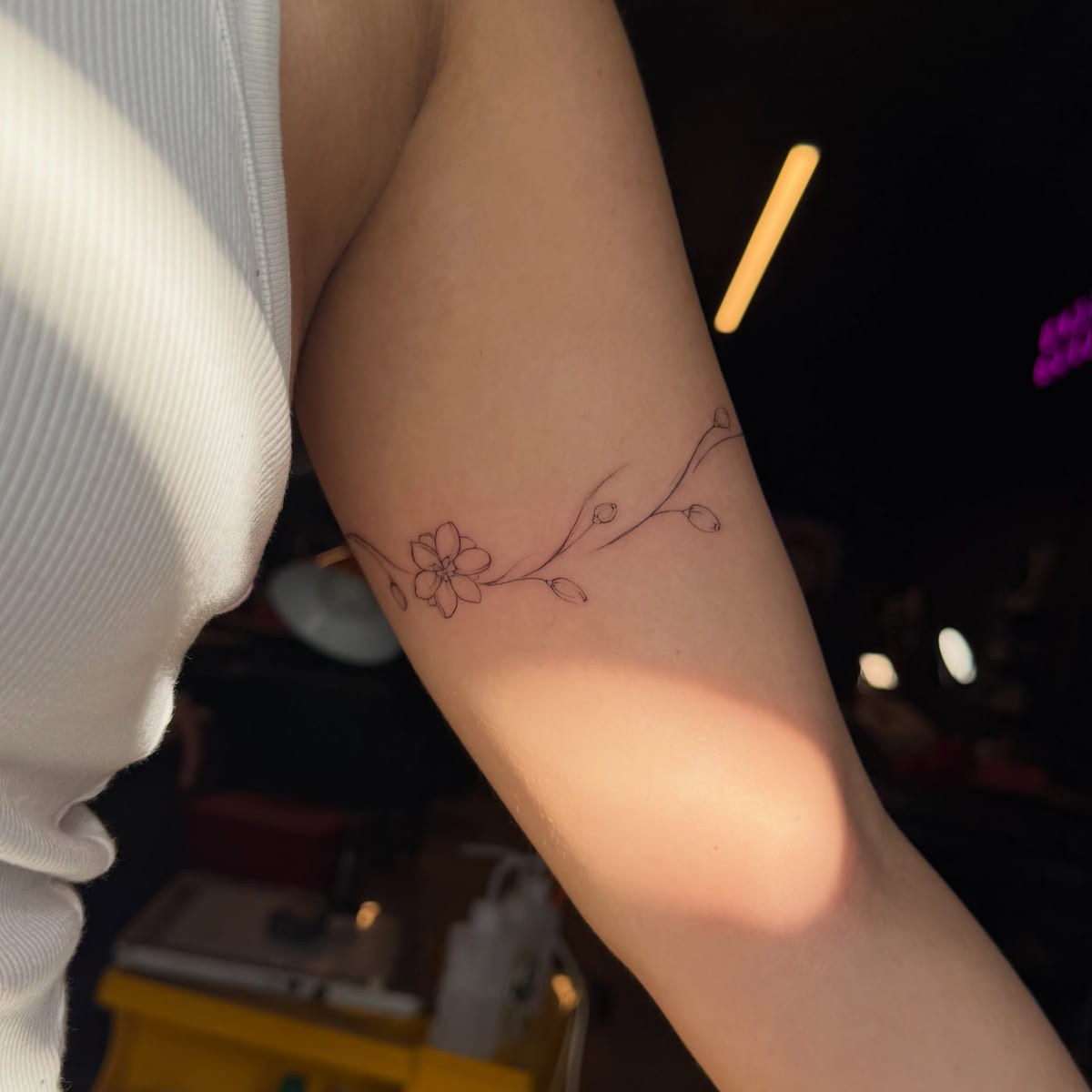 Flowering vine wrapping the arm, fine line tattoo