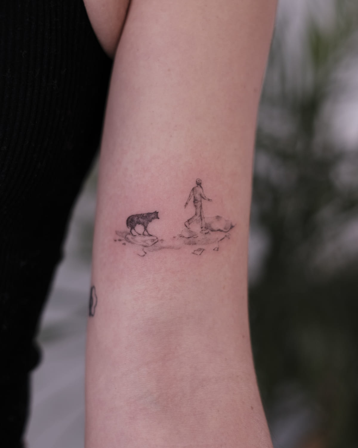 Tiny scene of a walking figure and an animal on small islands, fine line tattoo