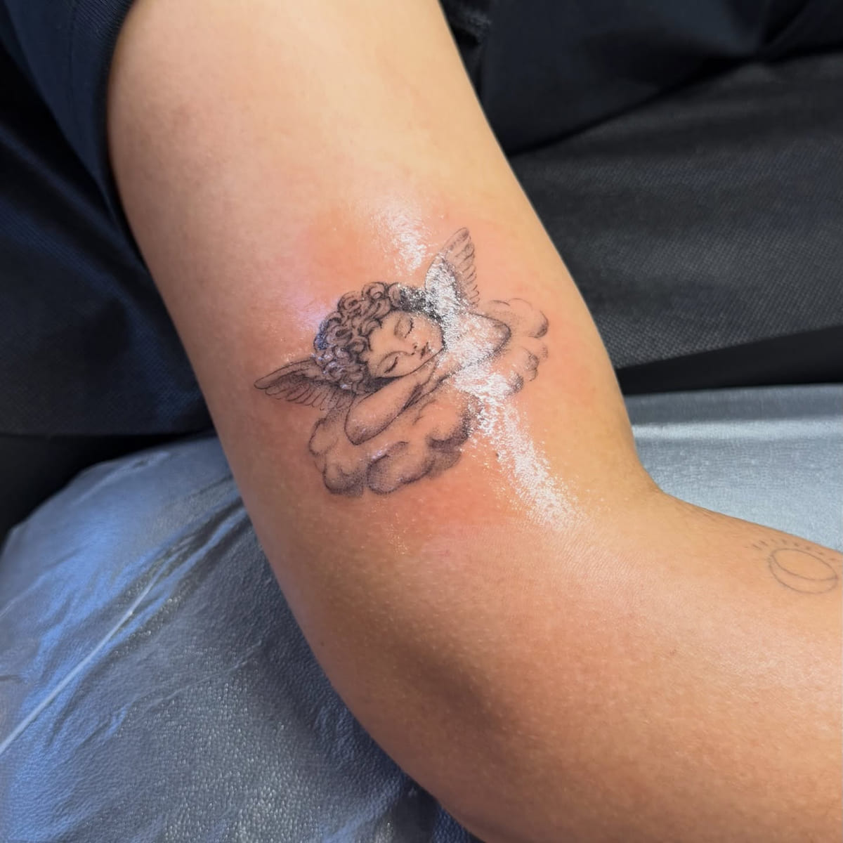 Sleeping cherub on a cloud, shaded, fine line tattoo