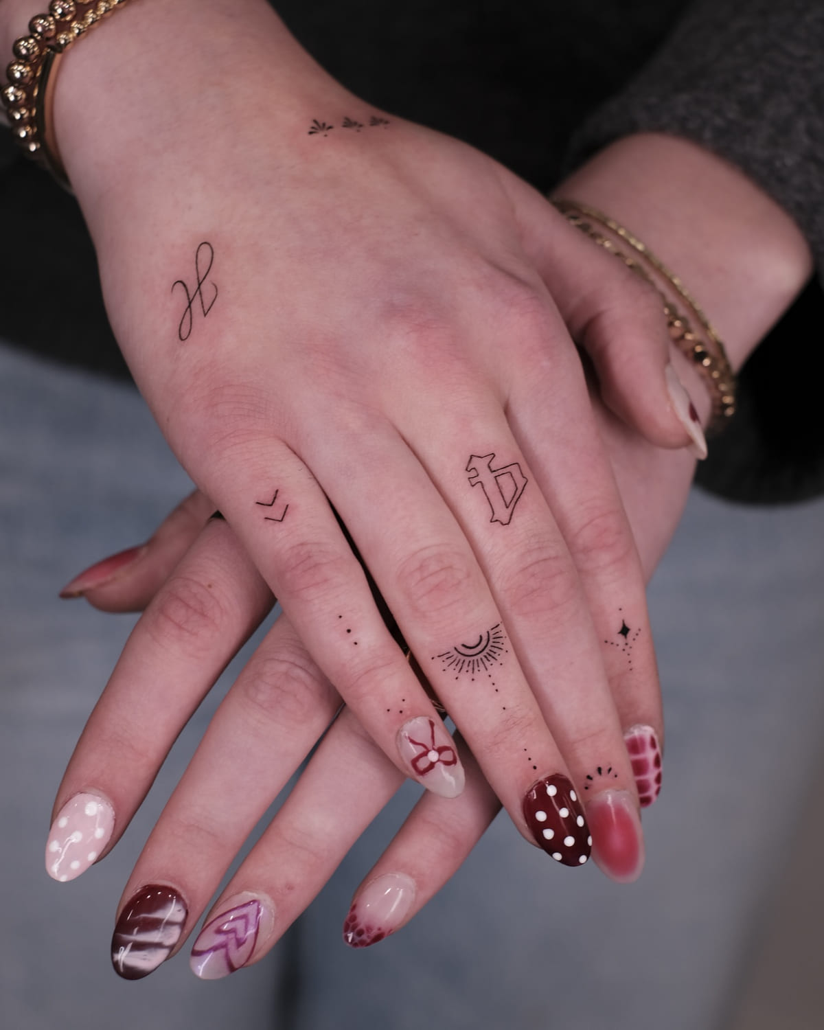 Tiny symbols and ornaments across the fingers and hand, fine line tattoo