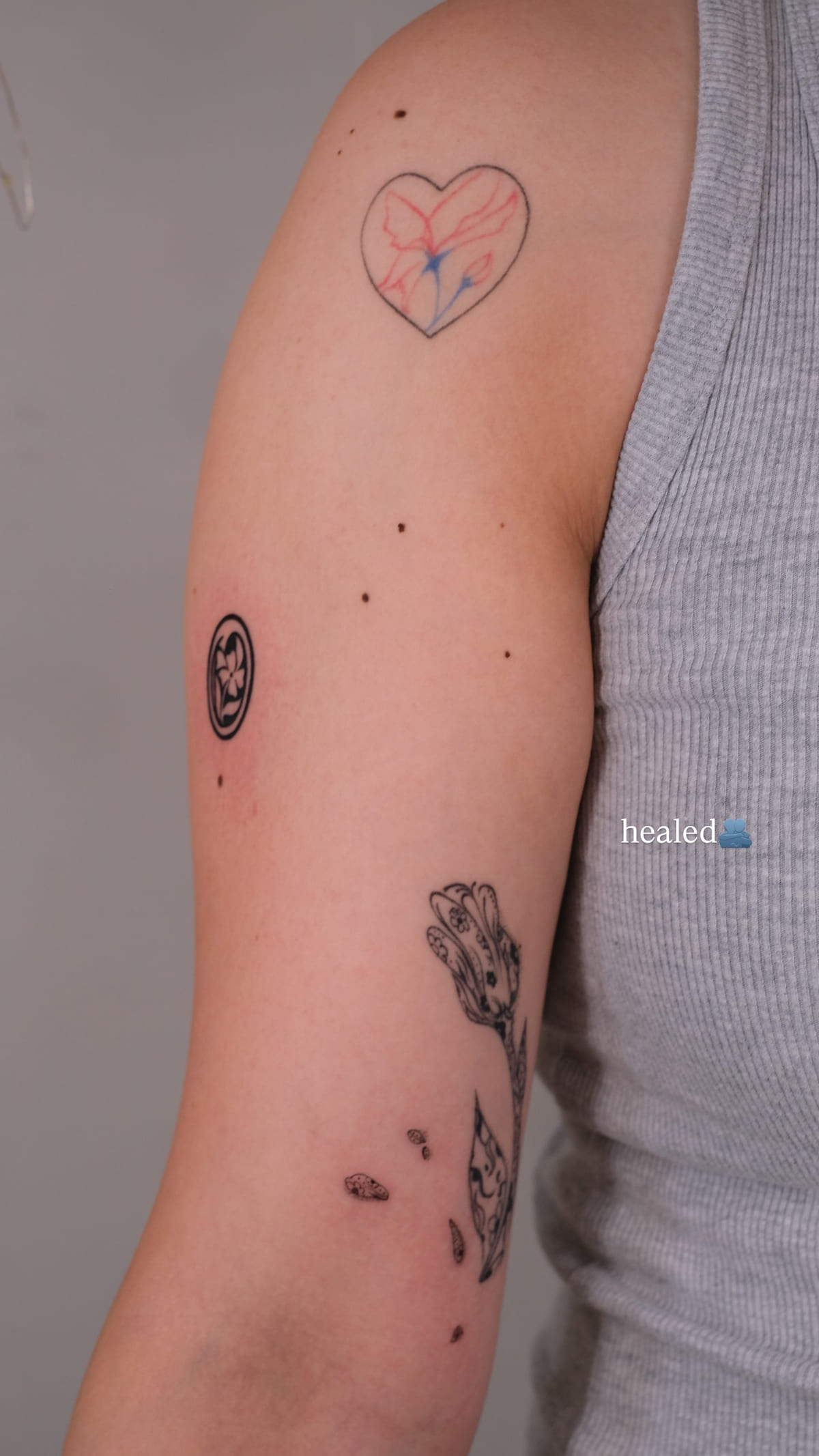 Red handwriting and a heart outline on an inner arm, healed fine line tattoo