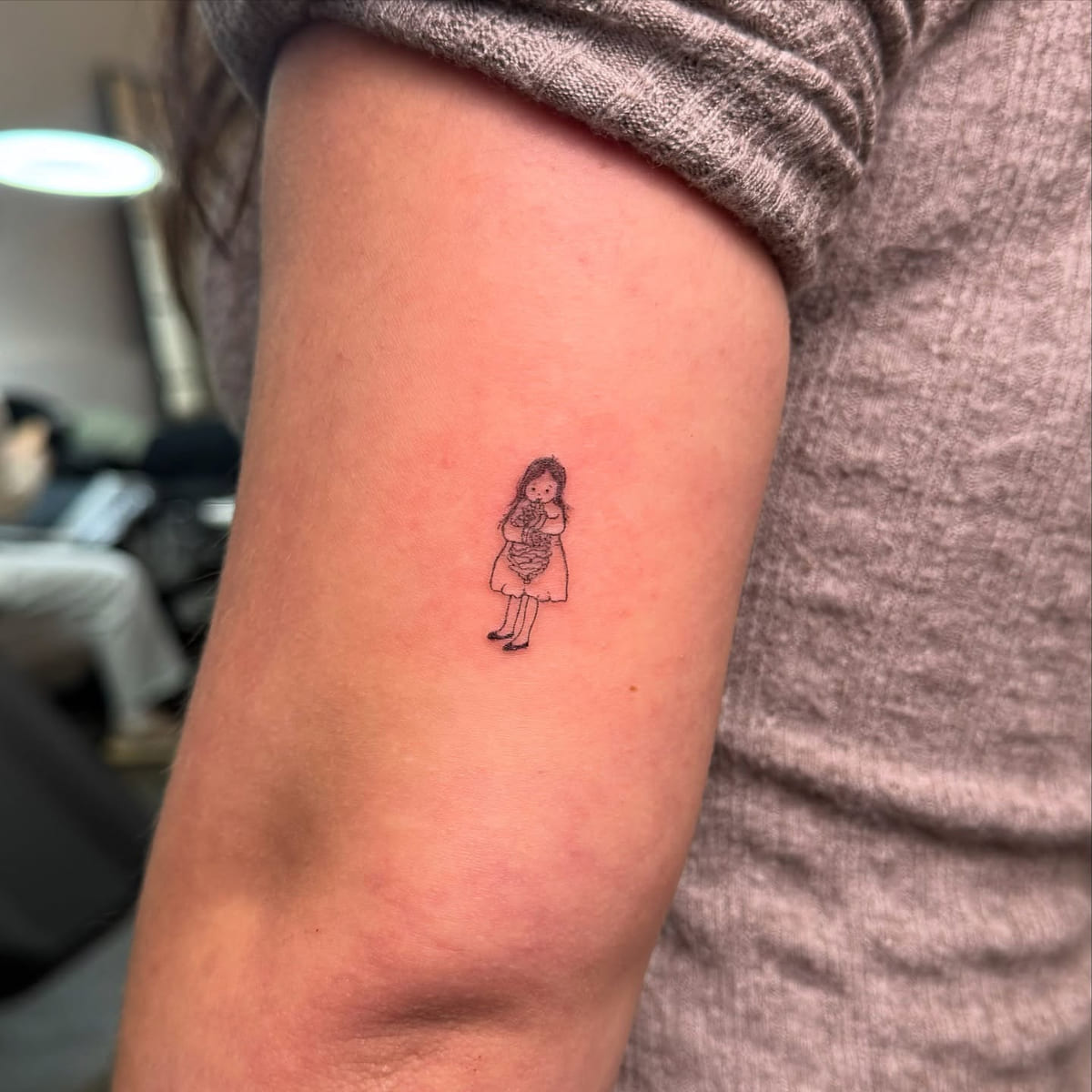 Tiny girl holding a bouquet, fine line tattoo