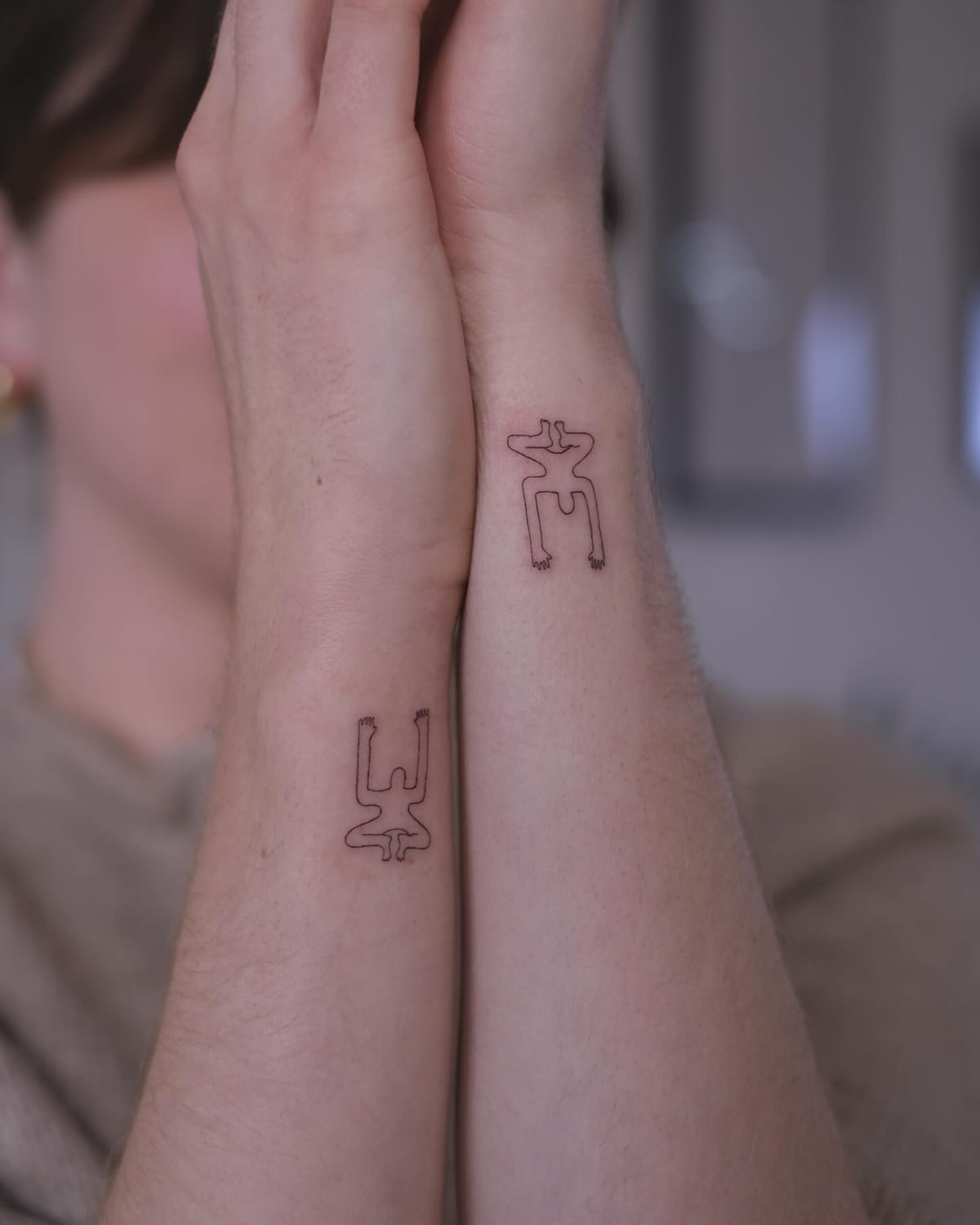Two small single line figures, one on each wrist, another view