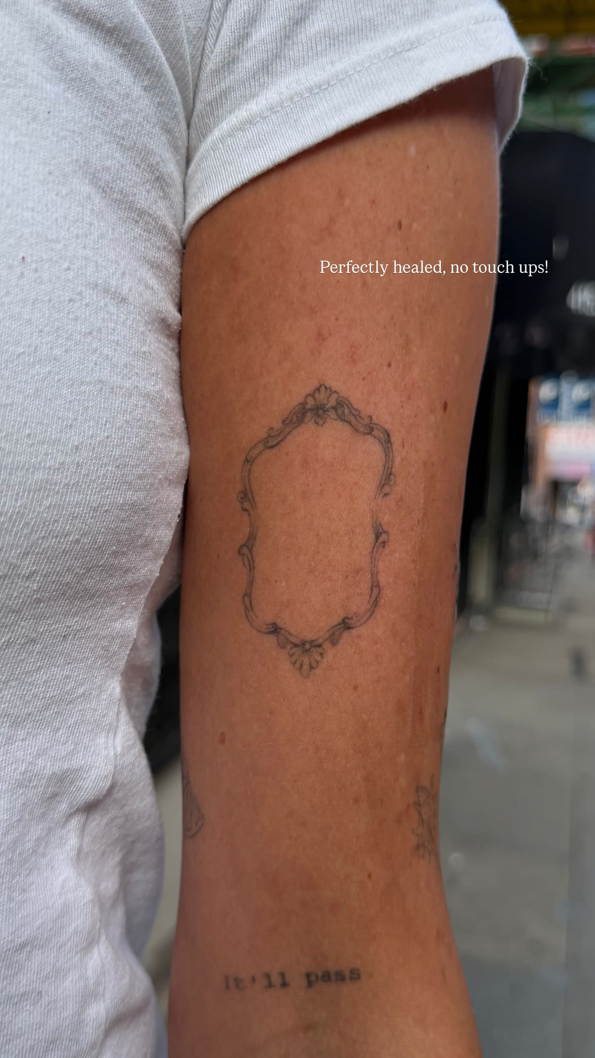Empty baroque frame on the back of an upper arm, healed fine line tattoo, healed