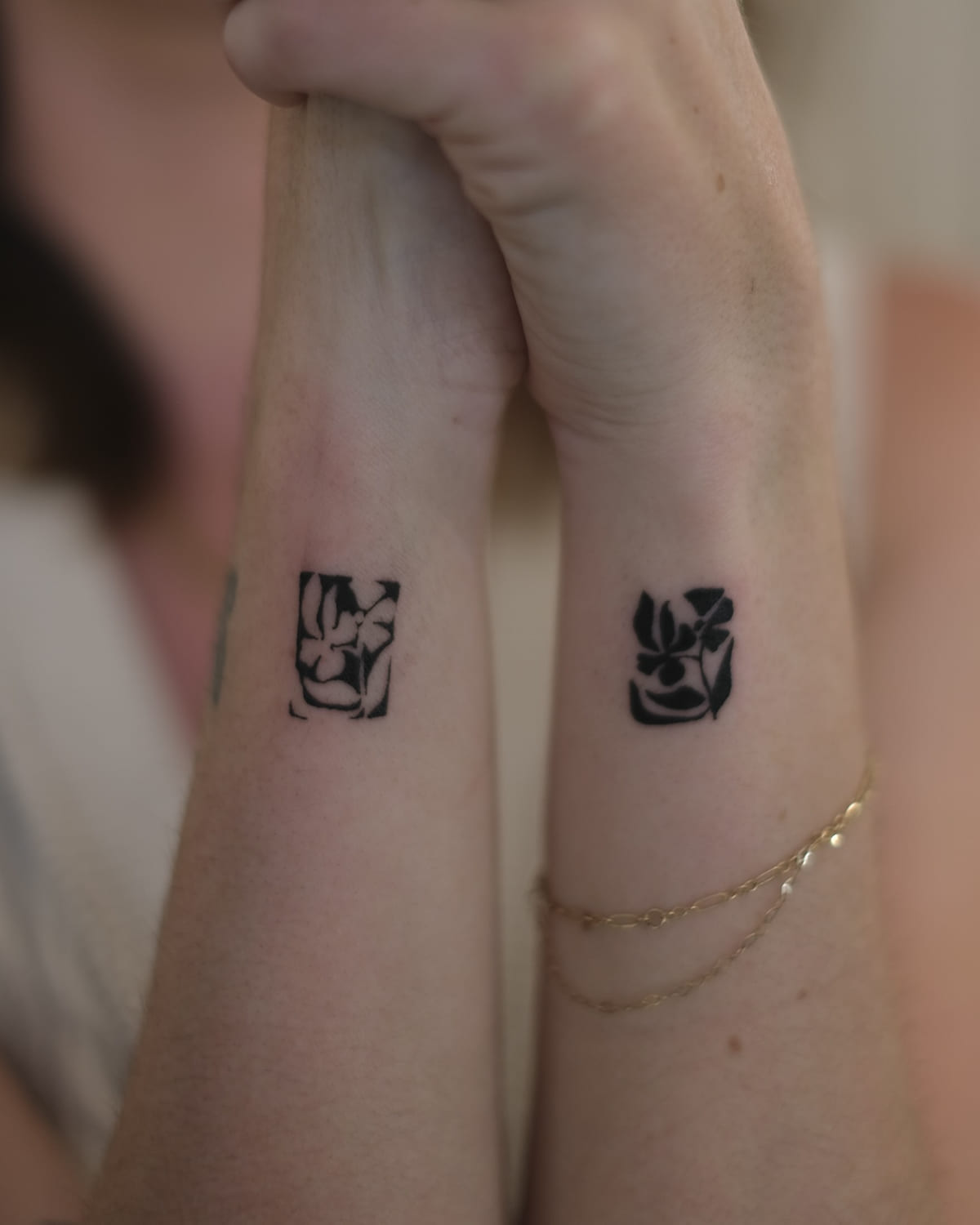 Two solid black flower blocks, one on each wrist, fine line tattoo