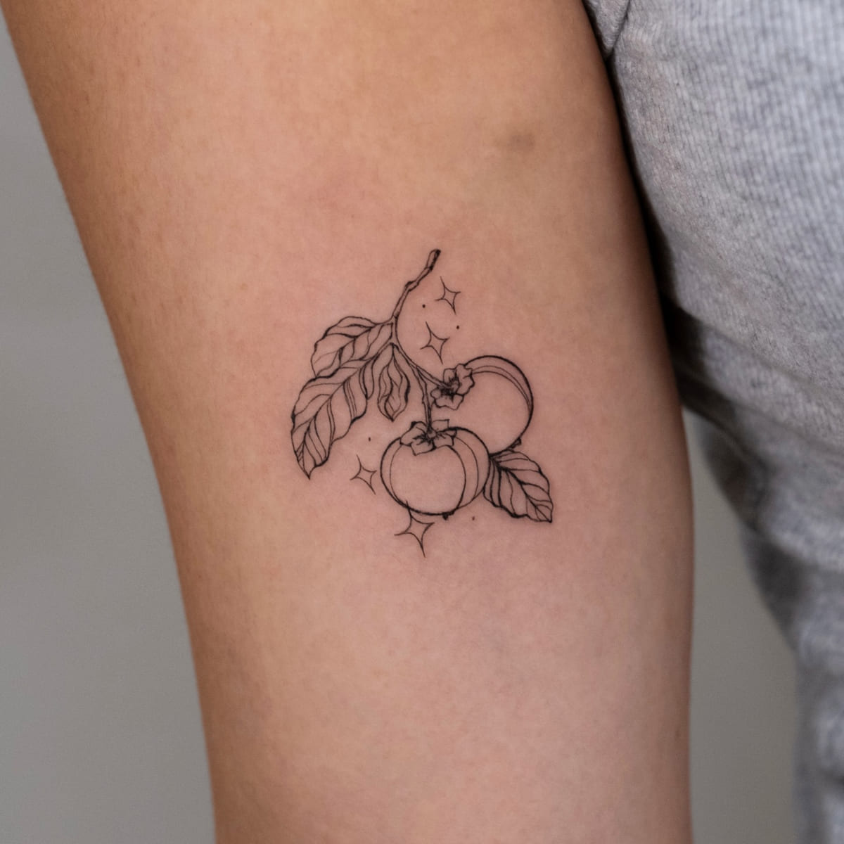 Two tomatoes on a branch with sparkles, fine line tattoo