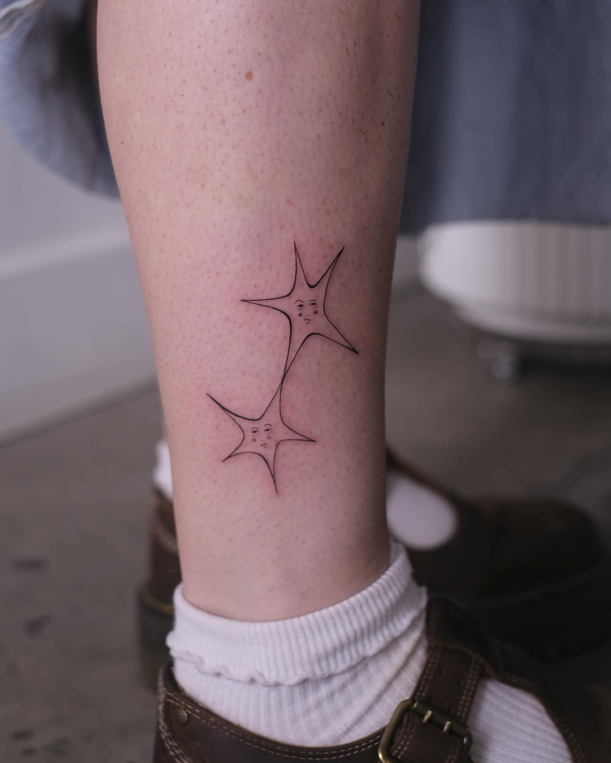 Two star characters with faces, fine line tattoo