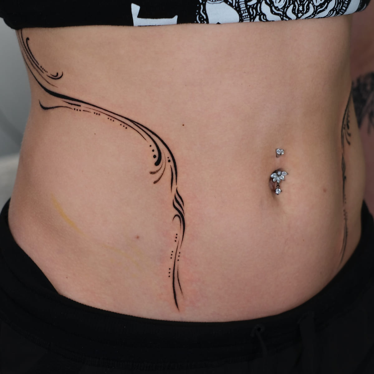 Ornamental flowing lines framing both sides of the abdomen, another view